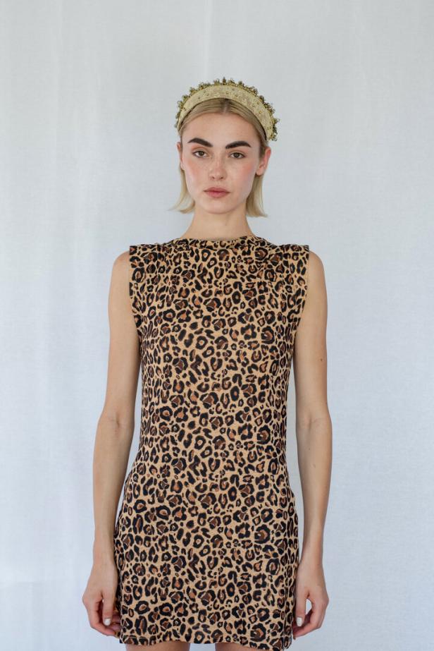 Eine Frau mit blonden Haaren trägt ein Kleid mit Leopardenmuster und ein goldenes Diadem.