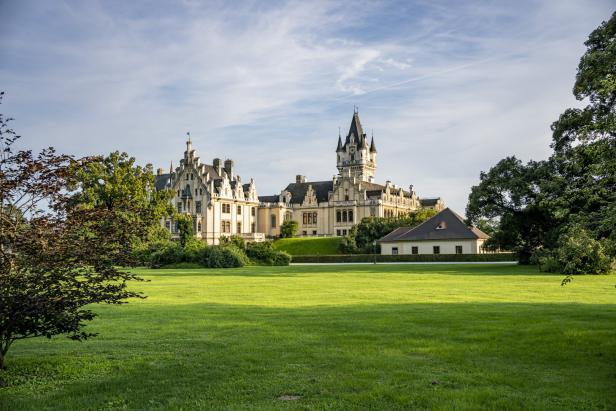 Das Schloss Grafenegg mit großem Turm und Zinnen in einem großen Park.
