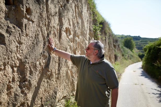 Ein Mann greift auf den steinernen Boden eine Wand neben der Straße am Wagram.