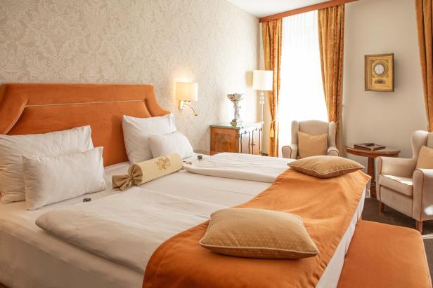 Ein Hotelzimmer mit einem Doppelbett, Sesseln und einem Nachttisch.