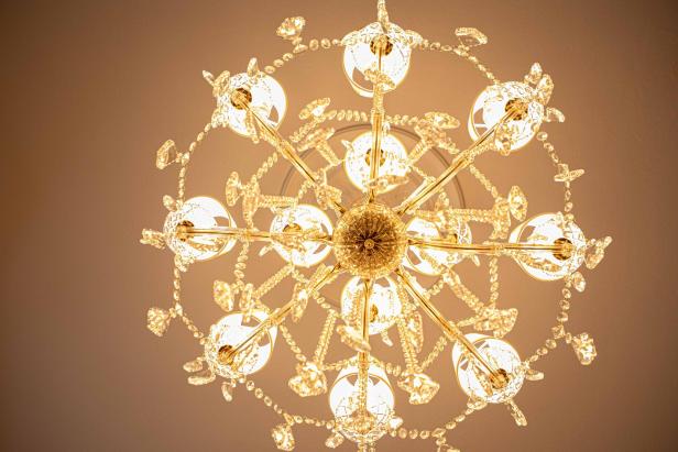 Ein funkelnder Kronleuchter mit goldenen Akzenten und Kristallverzierungen hängt an der Decke.