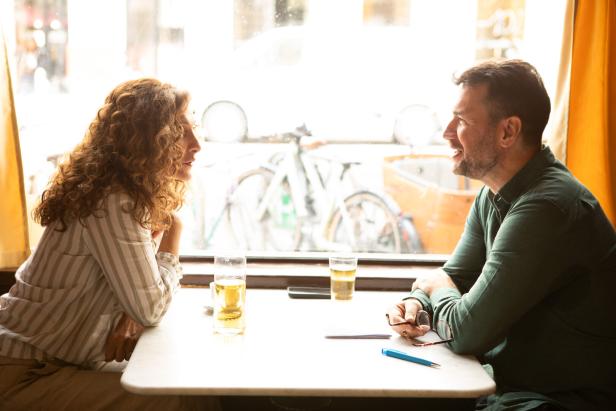 Ein Mann und eine Frau sitzen sich in einem Café gegenüber und unterhalten sich.