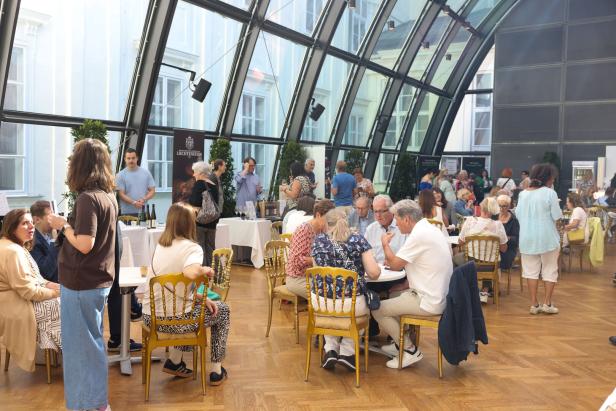 Menschen sitzen an Tischen im Wintergarten der Hofburg