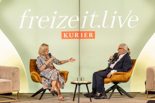 Martina Salomon und Mario Soldo sitzen auf Sesseln auf der Bühne und reden.