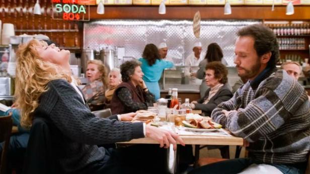 Szene aus „Harry und Sally“: Meg Ryan und Billy Crystal sitzen in einem vollen Restaurant.