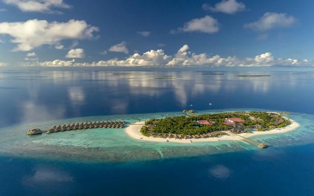 Insel von oben in einem Atoll, sie sit eher klein, es gibt ein paar Stege ins Meer.