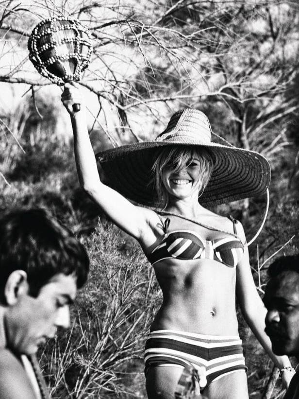 Brigitte Bardot mit einem großen Hut und einer Rassel in der Hand.