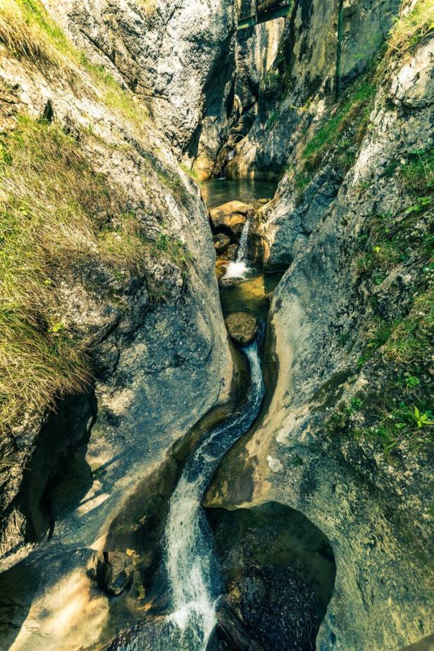 Ein kleiner Wasserfall fließt durch eine felsige Schlucht.