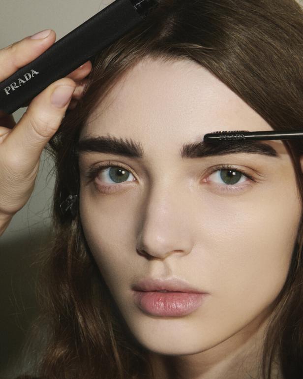 Einer Frau werden die Augenbrauen mit einem Produkt von Prada gestylt.