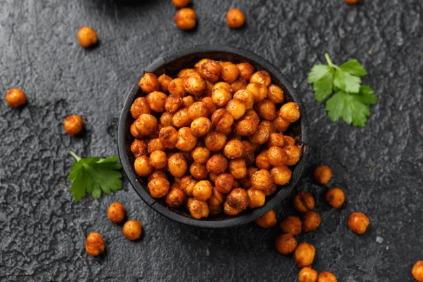 Roasted spicy chickpeas in rustic wooden bowl. Healthy snack.