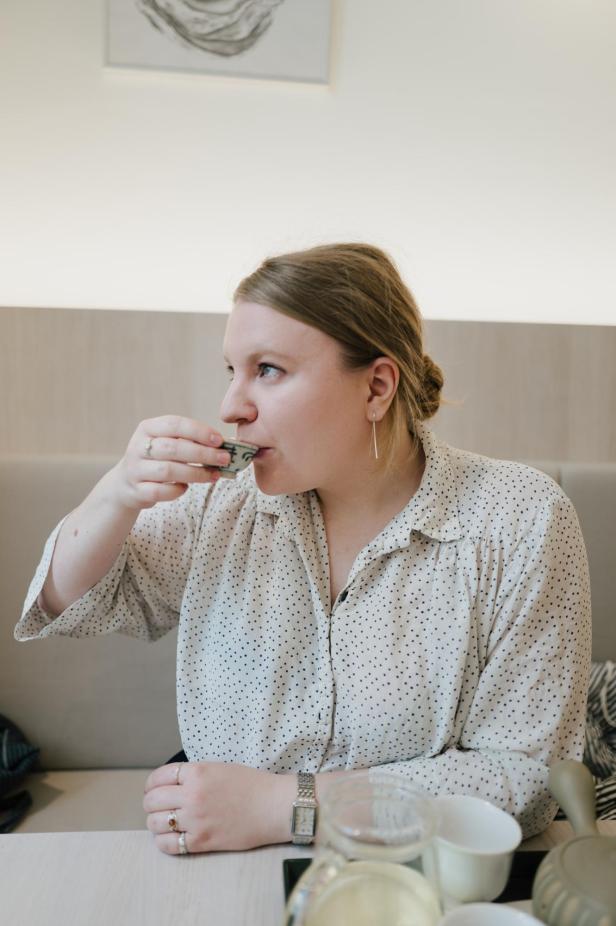 Ines Breiner ist im Organisationsteam des Vienna Tea Festivals. Sie sitzt auf einer Bank und nippt an einer Schale Tee. 