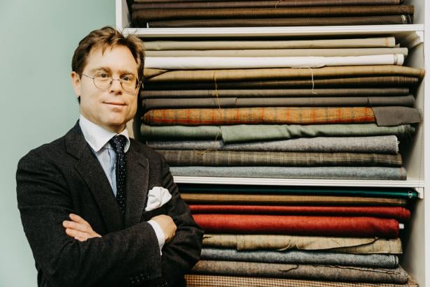 Maß-Salon Possanner Maß-Salon Possanner: Der Schneider steht vor einem Regal voll mit zusammengelegtem Stoff.