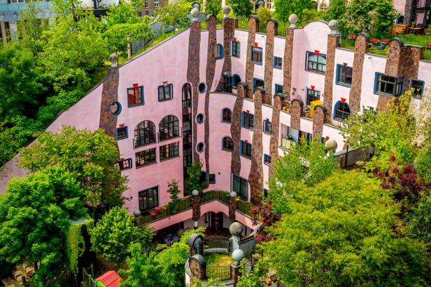 Eine Symbiose von Natur und Kunst: Ein rosarotes Haus von Hundertwasser mit frischer Begrünung.