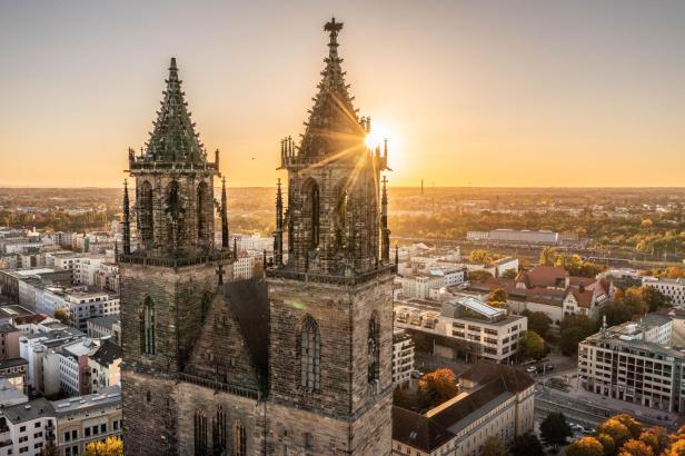 Blick auf den Magdeburger Dom mit seinen zwei Türmen während des Sonnenuntergangs über der Stadt.