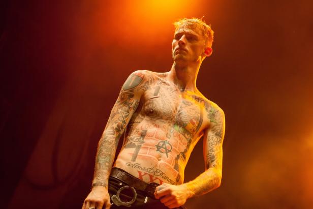 Rapper Machine Gun Kelly mit nacktem Oberkörper bei einem Auftritt in Moskau 2015 - Arme und Oberkörper sind voll tätowiert
