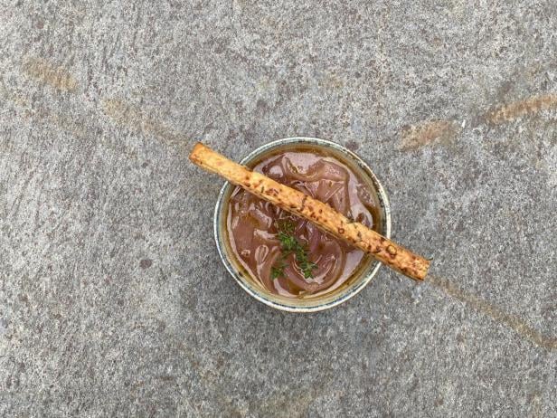 Eine Schüssel mit Zwiebel-Suppe und einem Cracker als Garnitur.