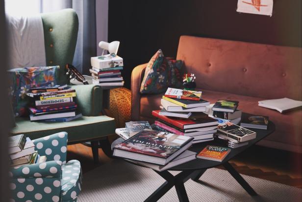 Ein Bücherstapel auf dem Wohnzimmertisch, ein anderer auf Sesseln.