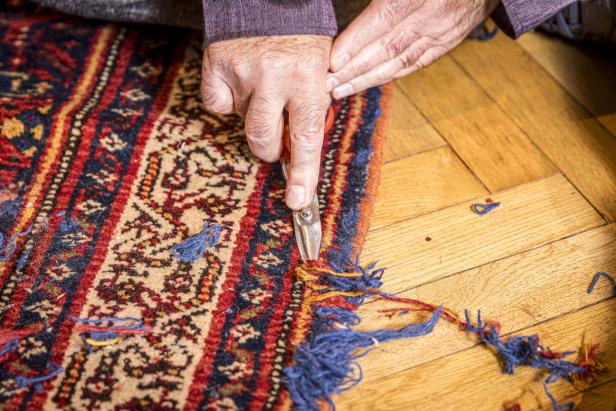 Mit einer Schere schneidet der Teppichmeister Fransen ab - dann erscheint das wirkliche Muster..