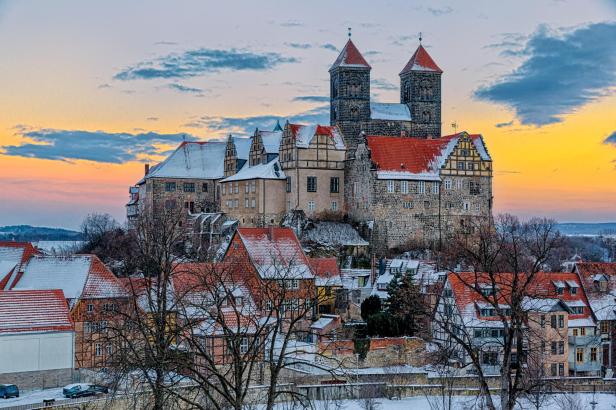 Das Schloss und die Stiftskirche von Quedlinburg im Sonnenuntergang und mit Schnee bedeckt