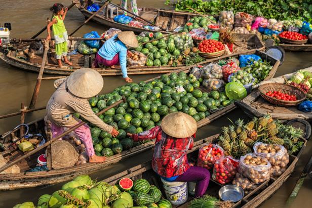 Frauen verkaufen Früchte auf einem schwimmenden Markt im Mekong Fluss