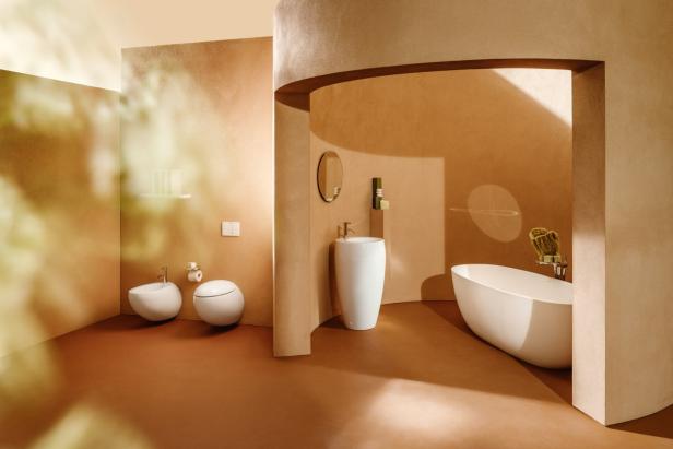 Modernes Badezimmer mit runden Formen aus der Kollektion ILBAGNOALESSI von LAUFEN in warmen Beigetönen mit freistehender Badewanne, Waschbecken und Bidet.