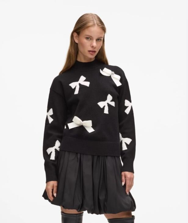 Eine Frau trägt einen schwarzen Pullover mit weißen Schleifen und einen schwarzen Rock von Karl Lagerfeld.