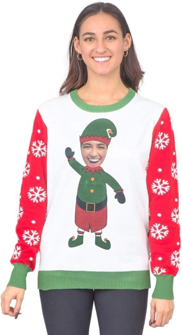 Eine Frau trägt einen Pullover mit roten Ärmeln und Schneeflocken, darauf ist ein lachender Elf mit ihrem Gesicht abgebildet.