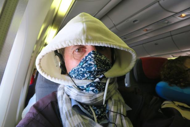 Mann im Flugzeug mit Maske und Schal