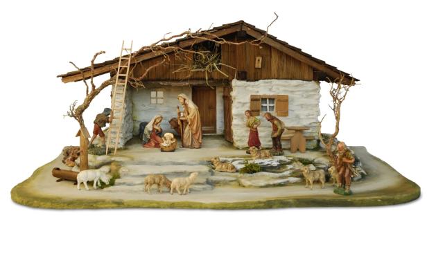 Krippe mit hölzernem Stall, mehreren Figuren in traditioneller Kleidung und Tieren auf einem ovalen Sockel.