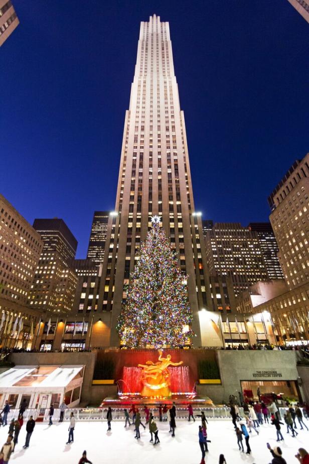 Vor dem Rockefeller Center steht ein beleuchteter Weihnachtsbaum über einer Eisbahn.