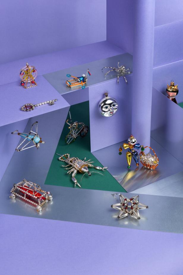 Verschiedene Schmuckstücke, darunter ein Skorpion und ein Auto, sind auf einer lila und grünen Oberfläche angeordnet.