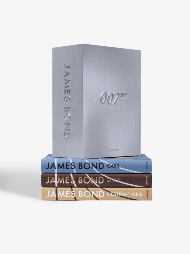 Drei Bücher über James Bond mit den Themen Autos, Stil und Reiseziele, darüber eine silberne Box mit 007-Logo.