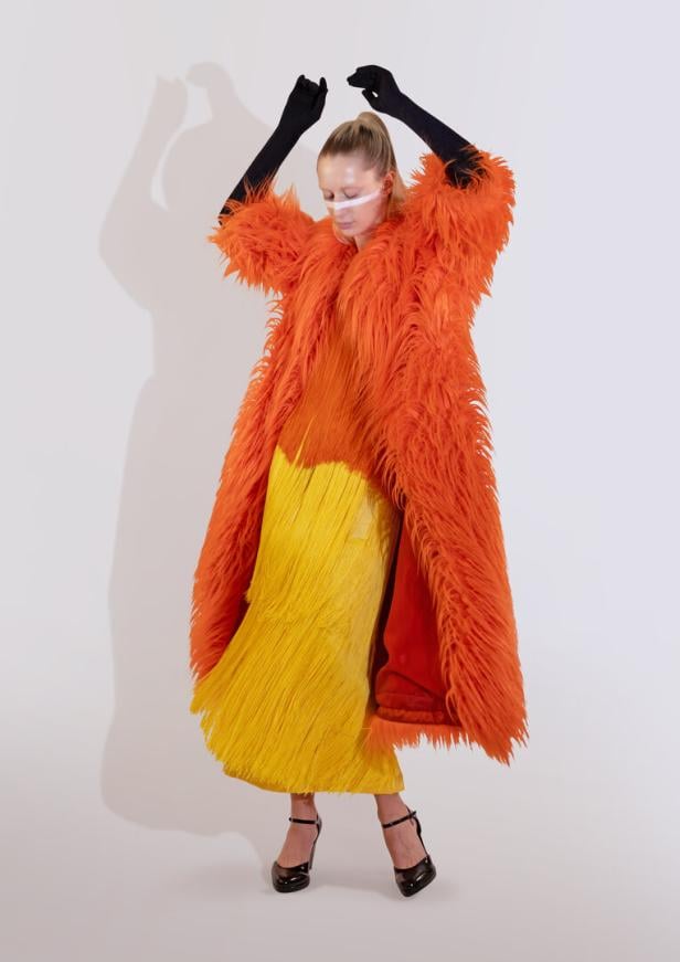 Eine Frau in einem orangenen fluffigen Mantel.