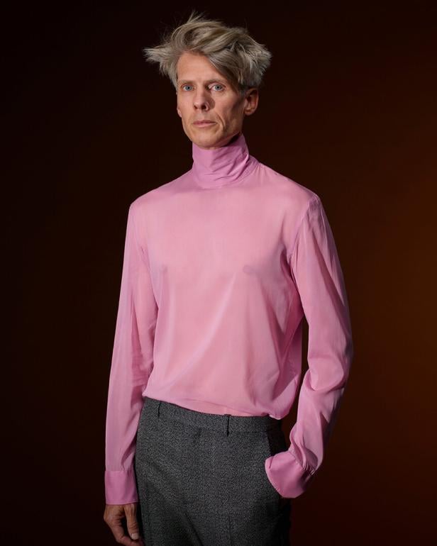 Ein blonder Mann in einem rosa Pulli