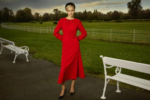 Eine Frau auf einer Wiese im roten Kleid. 