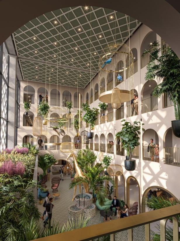 Großer, heller Saal mit vielen Pflanzen, goldener Giraffenstatue, Sitzbereichen und mehreren Menschen auf Balkonen und im Erdgeschoss.