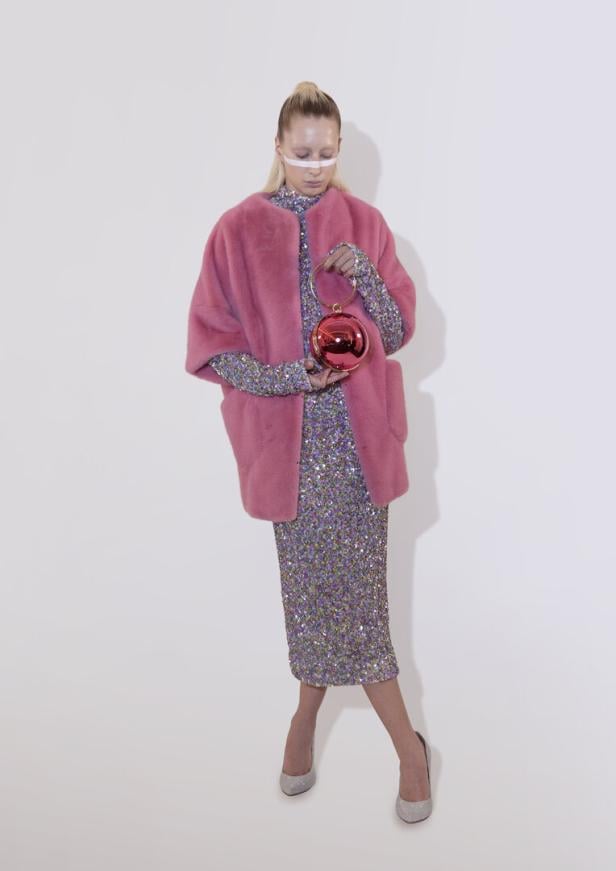 eine frau in einem pinken Mantel mit einem Paliettenkleid