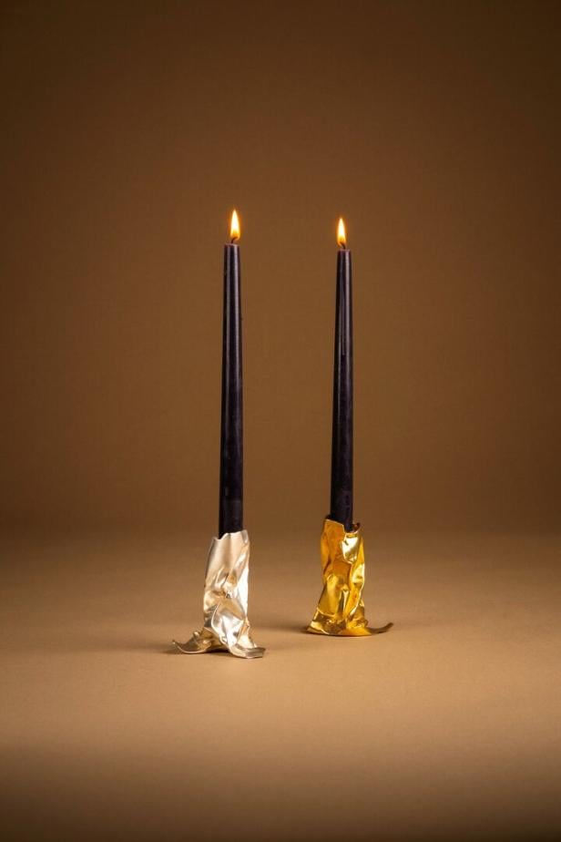 Goldener Kerzenständer mit schwarzen brennenden Kerzen