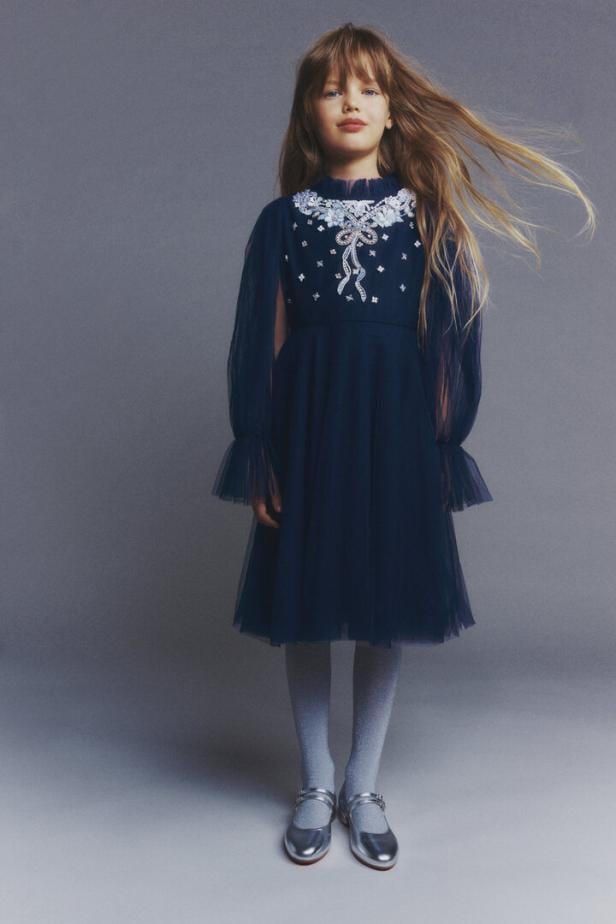 Ein braunhaariges Kind in einem dunkelblauen Kleid