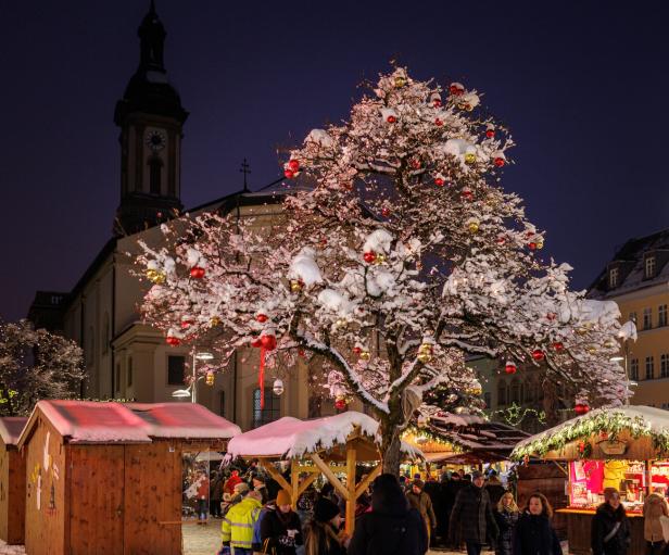 Ein Christkindlmarkt mit braunen Hütten und vielen Lichtern 