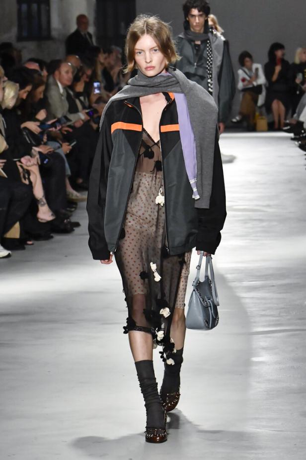 Eine Frau im Durchsichtigen schwarzen Kleid mit Bomberjacke