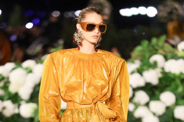 Eine Frau in gelbem, puffigem Oberteil mit riesen Sonnenbrillen