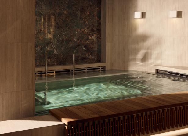 Modernes Spa mit elegantem Innenpool, Holzbank und stilvoller Beleuchtung.