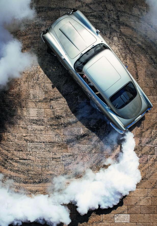 Ein silbernes Auto dreht auf Kopfsteinpflaster Kreise und hinterlässt dabei eine deutliche Rauchspur.