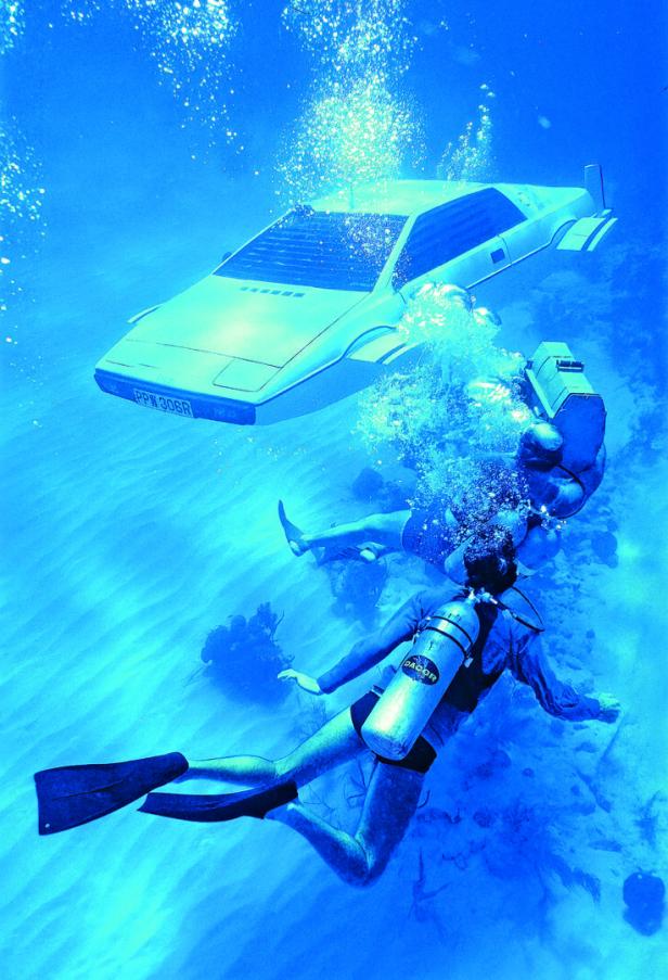 Zwei Taucher schwimmen unter Wasser neben einem weißen Auto, das wie ein U-Boot aussieht.