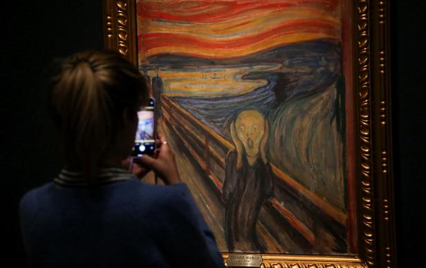 A visitor uses a smartphone to take a photograph of one of the versions of 'The Scream' by Edvard Munch in the National Museum in Oslo, Norway