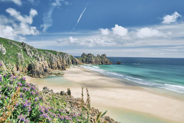 Scenic views across Pedn Vounder Beach towards Logan's Rock, Cornwall on a sunny June day.
