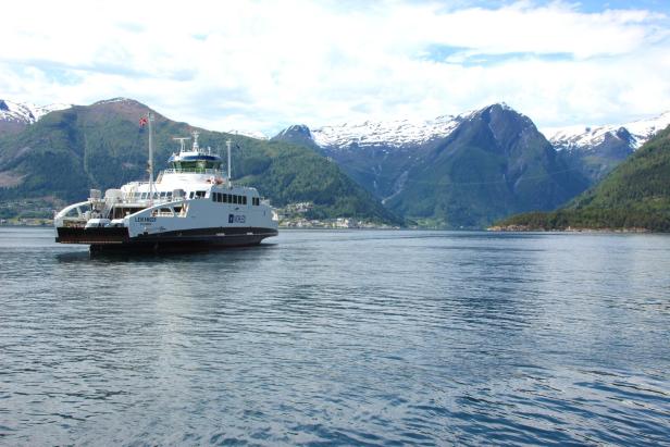 Eine Fähre, möglicherweise die "Leikanger", fährt auf einem Fjord vor einer Bergkulisse.