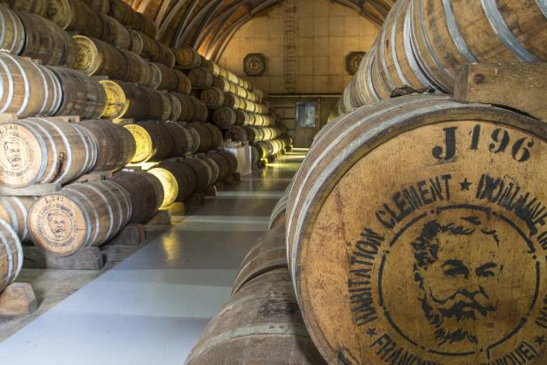 Im Lagerraum sind Reihen von Rumfässern der Marke Clement gestapelt.