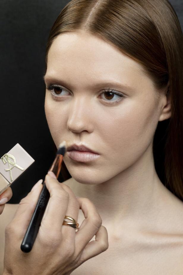 Pinsel mit Concealer: Lippe über den Lippenrand hinaus mit eher hellem Concealer und Pinsel grundieren. So entsteht eine ebenmäßige Basis.